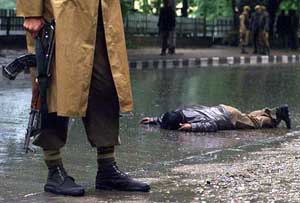 A soldier stands near the body of a suspected militant