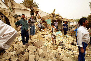 Iraqi civilians stand by the ruins of houses