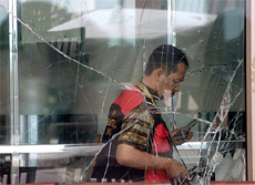 An Indonesian forensic expert inspects the bomb scene behind a cracked window near a fast-food outlet at Sukarno-Hatta airport 