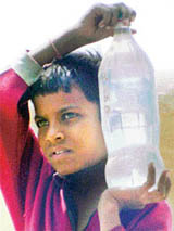 Carrying summer’s burden: Scorching heat coupled with water shortage forces this slum dweller to carry water for his family