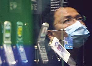 A visitor wearing a mask to ward off SARS looks at mobile phones displayed during an exhibition of international telecommunication technology in Shanghai, Chinas financial hub.