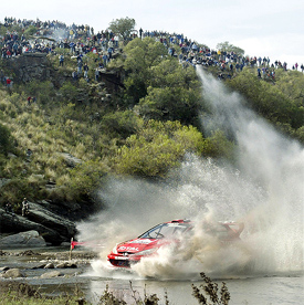 Finnish rally pilot Marcus Gronholm drives his Peugeot 206 through a river