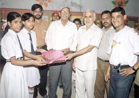 Cricket coach Ramakant Achrekar being presented with a memento by Modern Child School manager Mohinder Singh Yadav