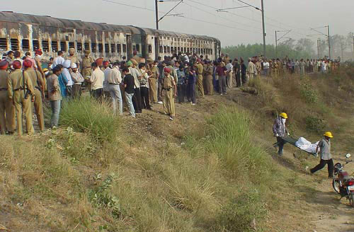 Rescue workers and onlookers crowd around the burned coaches.