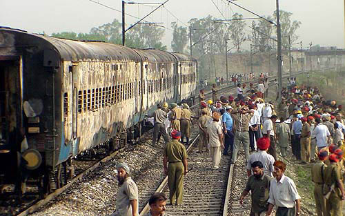 The three damaged coaches with policemen and onlookers around it.