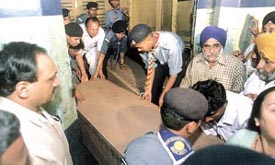 Relatives of one of the victims of the fire in Frontier Mail unloading the coffin as it arrived