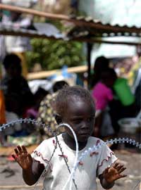 A young Congolese girl stands behind razor wire in a United Nations compound in Bunia
