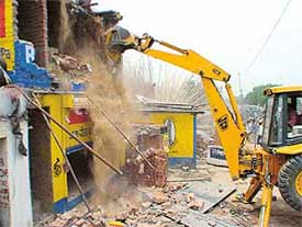 A JCB razes to the ground illegal structures at Attawa village