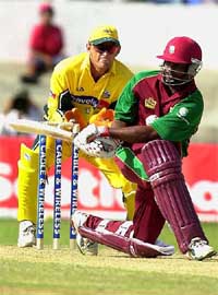 Brian Lara of the West Indies bats as Australias wicketkeeper Adam Gilchrist (left) looks on during the fourth one-day international at the Queens Park Oval