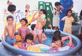 Students of Kiddies’ Paradise play in a water pool as part of their summer camp