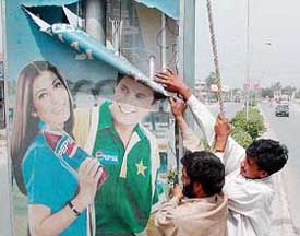 Workers remove a Pepsi advertisement in Peshawar