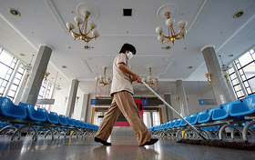 A Chinese cleaner swabs the floor at an empty waiting lounge at a Beijing railway station