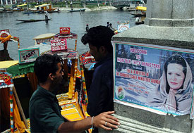 Two Kashmiri boatmen talk behind the poster of Ms Sonia Gandhi, Congress President, in Srinagar