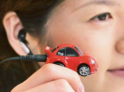 An employee of Japanese toy maker Takara Corp employee listens to music on the company's newly-developed compact audio player 'Music Choro-Q New Beetle COX model' in Tokyo