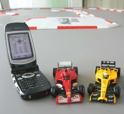 An employee of Japanese toy maker Konami points a mobile phone towards his invention, a toy formula car called "MICRO iR" during a demonstration at the company's office in Tokyo. 
