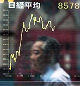 A Japanese businessman is reflected on a glass window, displaying the stock index price