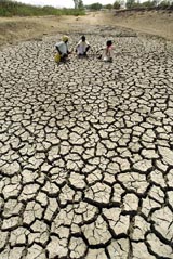 Villagers sit on their parched farm land in Turkapalli village