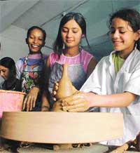 Students work with clay on a potter’s wheel at a workshop