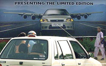 A Maruti car passes a billboard advertising the company's latest model in New Delhi 