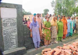 Women activists of the SAD-BSP combine stand near the controversial stone 