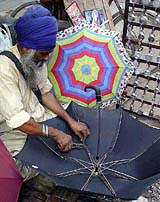A man repairs an umbrella following pre-monsoon showers in Ambala