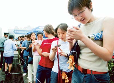 A Chinese woman smiles after receiving a card noting her place in line, after having already waited for six hours, to buy a new type of mobile phone SIM card in Beijing. China 