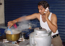 Raju, a teastall owner, prepares tea and attends to business calls simultaneously at Ambala.