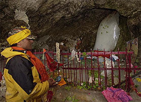 A devout offers prayers near the ice lingam of Lord Shiva at the holy cave shrine of Amarnath