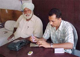 A manager of a firm examines a currency note while the customer waits for the counting process to complete