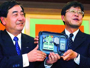 Sharp Corp Corporate Director Yoshiki Sano (L) and Texas Instruments Japan Ltds Akikazu Okano show a reference design for GSM/GPRS camera phones at a joint news conference in Tokyo.