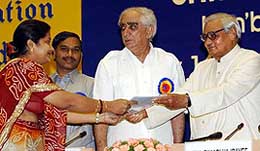 Prime Minister Atal Bihari Vajpayee presents an insurance certificate to a woman as Union Finance Minister Jaswant Singh looks on