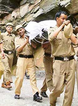 Policemen carry a body during rescue operations at Pulia Nullah, near Kulu