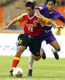 East Bengals Baichung Bhutia struggles for the ball with Persita Club's Maman 