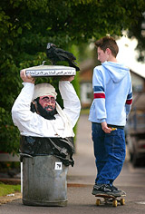 A skateboarder rides past a scarecrow representing Osama bin Laden