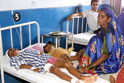 A mother sits beside her children on a hospital bed in Jammu