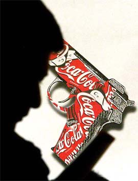 A man listens at a news conference in front of an anti-Coca-Cola advertisement in Bogota