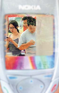 Chinese buying new mobile phones are seen through a mobile phone cover displayed at a store in Beijing