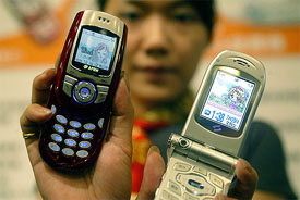 An employee of Taiwan's Eastern Broadband Telecom displays two new third-generation mobile phones 
