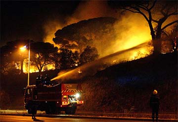 Firemen aim their hoses at a blazing forest at the Maures hills 