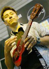 An employee of Yamaha Corp demonstrates the company's new prototype electric ukulele "EZ-UK" 