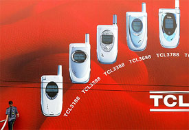 A security guard stands in front of a billboard advertising Chinese-made mobile phones in Guangzhou