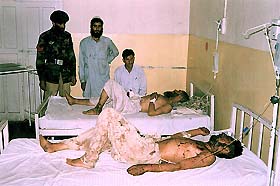 Two Pakistanis, injured in a blast set off by a fire near an explosive store, lie in a hospital bed in Gilgit