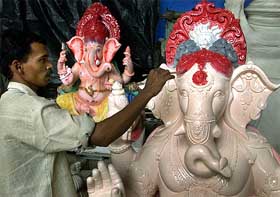 An artist gives finishing touches to an idol of Lord Ganesha at a workshop in Mumbai 