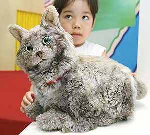 A visitor touches a SegaToys Cos pet robot at the 2003 Japan Toy Show in Yokohama, south of Tokyo.