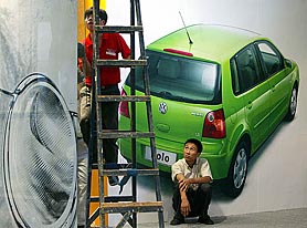 Chinese workers install billboards at a car show in Beijing on Tuesday