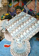 Mohammad Akbar holds a kite, made out of currencies, at his shop in New Delhi 