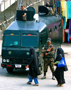 A veiled women walk past a BSF armoured vehicle in Srinagar