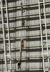 A file photo of workers standing on scaffolds outside Olympic International Broadcasting centre in Athens