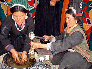 Two Ladakhi women use traditional method to extract oil from seeds at the Women Alliance Festival in Leh
