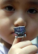 A Taiwanese boy puts a 1.18-inch-long solar energy toy car on his thumb in Taipei